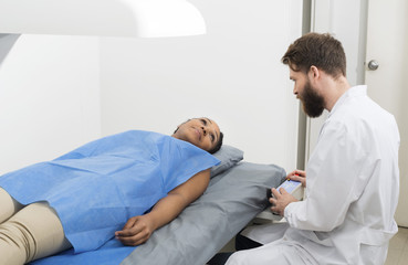 Fototapeta premium Woman Looking At Male Doctor Examining Her At Clinic
