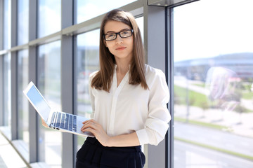 Fototapeta premium Modern business woman typing on laptop computer while standing in the office before meeting or presentation