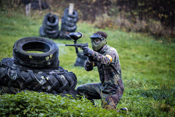 Paintball player aiming and hiding - obrazy, fototapety, plakaty