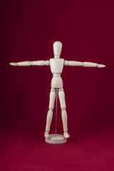 a wooden dummy posing with a red background