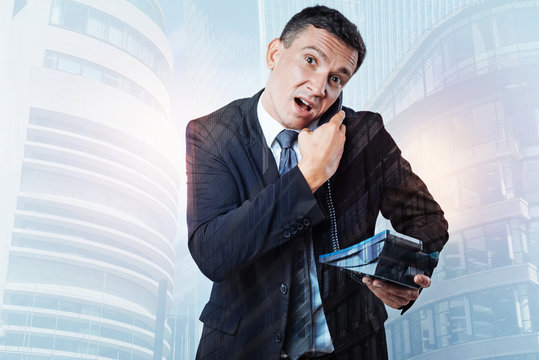 Nice stressed out businessman holding receiver - Powered by Adobe
