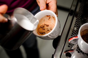 Barista making coffee pouring milk into cup