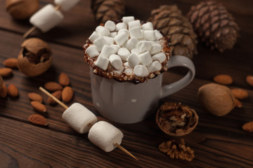 cup of hot cocoa or chocolate with marshmallow, candy and cone on wooden rustic background