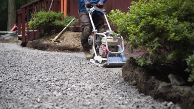 Closeup of the vibratory plate compactor as it settles the dirt and gravel at the start of the hardscaping process.