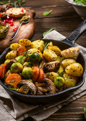 Fototapeta na wymiar Fried potatoes with vegetables and herbs on wooden background. Healthy food concept.