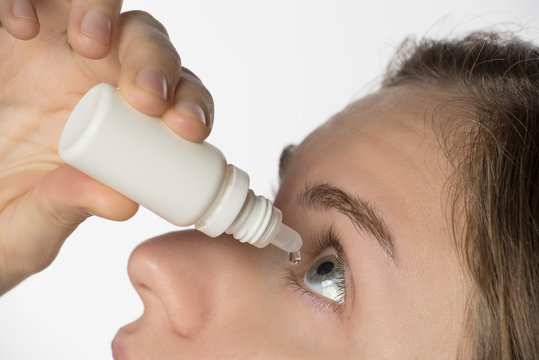 The girl bury drops in the eye with contact lenses from a white bottle