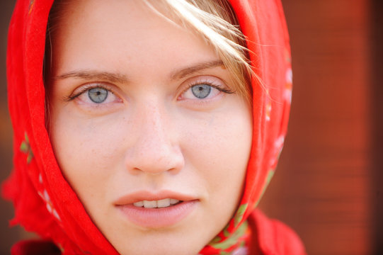 A russian blonde with blue eyes in a red kerchief is working on the farm. The concept of female beauty and perfection, russian beauty.