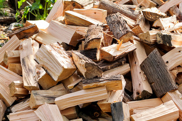 A pile of chopped firewood logs ready for the winter. Cut logs fire wood. Hardwood, wood and lumber industry. Heating season, winter season. Renewable resource of energy. Environmental concept.