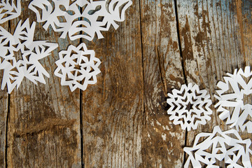 Christmas background with white paper snowflakes on rustic wood texture. Top view with copy space 