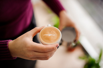 Woman in purple shirt holding a cup of latte