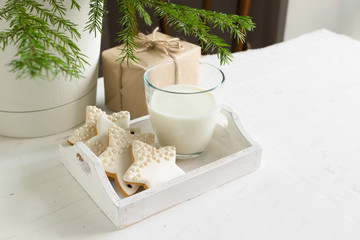 A traditional treat Christmas cookies and a glass of milk on white wooden table. New year's concept. Kinfolk.