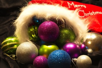 An assortment of sparkling Christmas balls with rough and smooth textures fitted snuggly in a red and white Christmas stocking