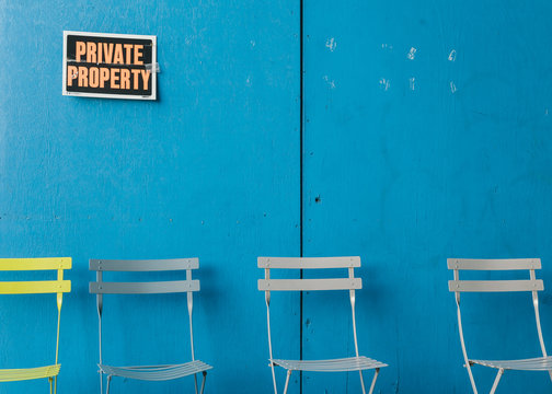 Empty chairs and a blue wall with a private property sign