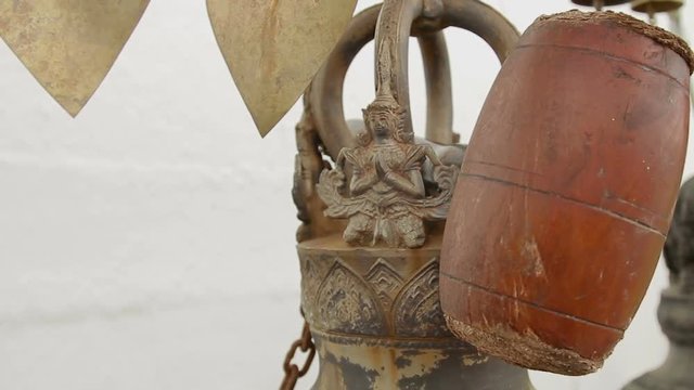 Mallet and decorative figure on sacral gong (bell) in Wat Saket Ratcha Wora Maha Wihan (the Golden Mount). Bangkok, Thailand.