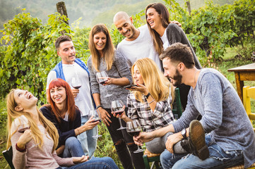 Happy friends having fun outdoor - Young people drinking red wine at harvest time in farmhouse vineyard winery - Youth friendship concept with mates using smartphone for a live mobile phone call