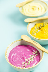 Snacks in the form of sauces from carrots, beets and hummus from chickpeas. in bowls on a contrasting blue background