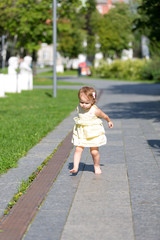 The little girl runs barefoot through the garden path