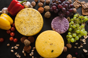 Food composition of dairy gourmet products, top view. Quality sorts of cheese with variety of appetizers and vegetables around