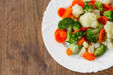 Mixed vegetables. cauliflower, broccoli and carrots in plate on a wooden background. with copy space. top view