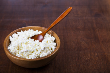 Cottage cheese and spoon in a wooden bowl