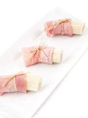 Pl&aacute;tanos cortados en trozos con jam&oacute;n york sobre un plato blanco. Vista superior y de cerca. Formato vertical