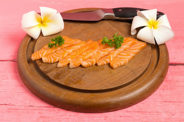 salmon sushi on cutting board with flower on wood color pink