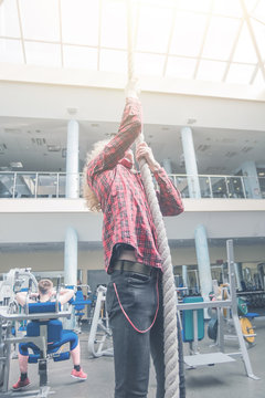 Man In Red Shirt Climbing The Rope In Gym