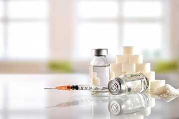 Insulin vials and syringe on white table with background windows