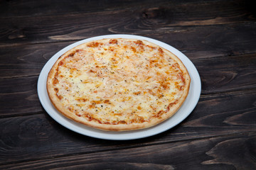 Pizza margarita on a white plate, and a black wooden table