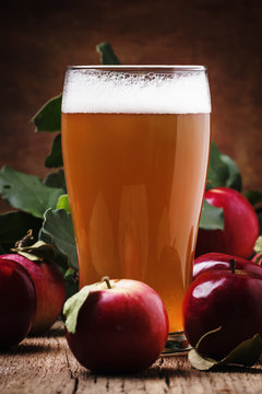 Apple cider in a large beer glass, old wooden background, selective focus