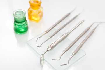 Dental mirror and other professional tools set in dentist clinic on white desktop, macro shot of shiny basic metal medical equipment