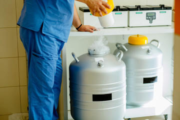 Closeup of male technician holding rack in nitrogen tank. Cryosample taken out of Liquid Nitrogen...