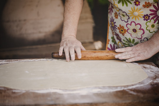 Baker kneading dough with rolling pin