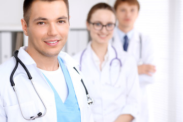 Fototapeta premium Cheerful smiling male doctor with medical staff at the hospital