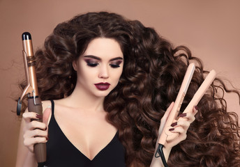 Curly hair. Beauty Close-up of brunette girl with blowing hairstyle holding curling and...