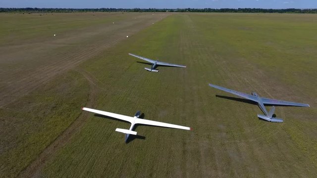 Three glider plane lies in the field on a sunny day, aerial shooting