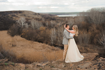 happy young couple hugging on the edge of the mountain, in the background a very beautiful landscape