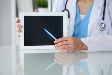 Female doctor pointing into tablet computer, close-up of hands. Physician ready to examine and help patient. Medicine, healthcare and help concept
