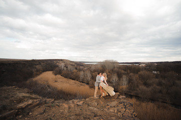 Obraz premium happy young couple hugging on the edge of the mountain, in the background a very beautiful landscape