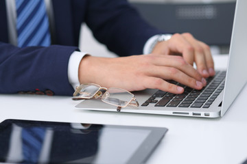 Businessman working by typing on laptop computer. Man's hands on notebook or business person at workplace. Employment  or start-up concept