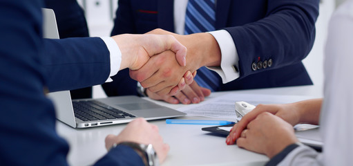 Business handshake at meeting or negotiation in the office, close-up. Partners are satisfied because signing contract or financial papers