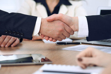 Close up of business people shaking hands at meeting or negotiation in the office. Partners are...