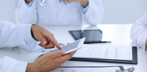 Group of doctors at medical meeting. Close up of physician using touch pad or tablet computer.