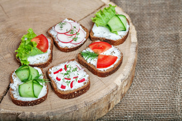 Sandwiches with cheese and vegetables on a wooden stand.  The concept of healthy eating and vegetarianism.