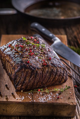 Beef steak. Juicy Rib Eye steak in pan on wooden board with herb and pepper