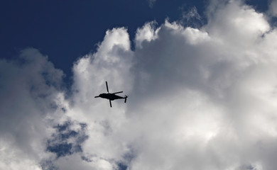 Fototapeta na wymiar Helicopter flying in cloudy sky