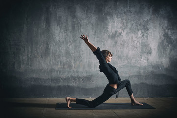 Beautiful sporty fit yogini woman practices yoga asana Virabhadrasana 1 - warrior pose 1 in the...