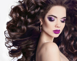 Fototapeta premium Healthy hair. Bright violet makeup. Beautiful Brunette Girl portrait. Beauty glitter eyeshadow. Model Woman with long blowing hairstyle isolated on white background.