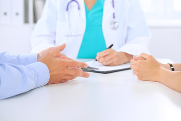 Doctor and patient couple are discussing something, just hands at the table