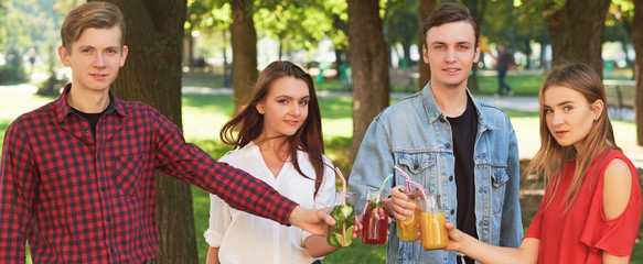 Healthy nutrition. Group of friends drinking fresh juice detox on green nature background. Youth lifestyle, vegetarian diet to go, fitness food, successful weight loss concept